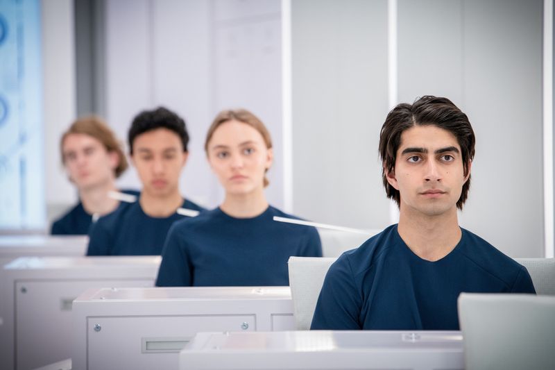 Peter (Viveik Kalra, rechts) und Sela (Lily-Rose Depp, Mitte) gehen im Raumschiff wie alle anderen Crewmitglieder ihren Aufgaben nach.