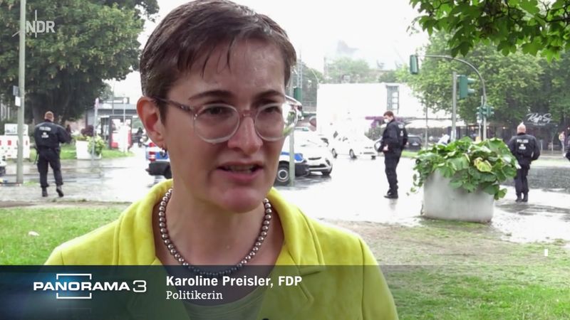 Karoline Preisler (FDP) steht im Regen, aber sie lässt scih nicht unterkriegen, sagt sie im Angesicht diverser Anfeindungen am Rande einer "Querdenker"-Demonstration. Sie war selbst schwer an COVID 19 erkrankt und ist nun eine der Hauptprotagonistinnen des "Panorama 3"-Films.