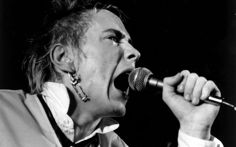 50 Jahre liegen die Anfänge von Punk nun zurück. Als Sänger der Sex Pistols war John Lydon unter dem Namen Johnny Rotten, hier zu sehen bei einem Liveauftritt im Dezember 1976, eine der großen Ikonen der Bewegung. Anlässlich Lydons 70. Geburtstags am Samstag, 31. Januar 2026, geht die Galerie der Frage nach, was aus den Punk-Größen von damals geworden ist.