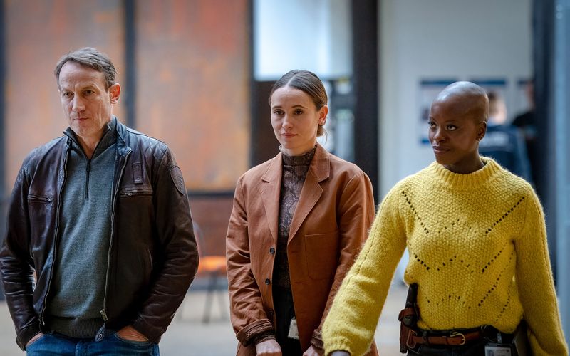 Das wohl einmalige Kommissars-Trio zum Ostermontag 2025: "Tatort: Im Wahn" sucht einen Messerstecher-Mörder in einer Menschenmasse am Bahnhof von Hannover. Es ermitteln Thorsten Falke (Wotan Wilke Möhring), Yael Feldman (Peri Baumeister, zweite von links), Anaïs Schmitz (Florence Kasumba) und eine ominöse KI namens Kroisos.