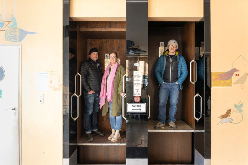 Kira Weißbach, Chefin des Großmarkts, nimmt Sebastian Bezzel (links) und Simon Schwarz im Paternoster mit.
