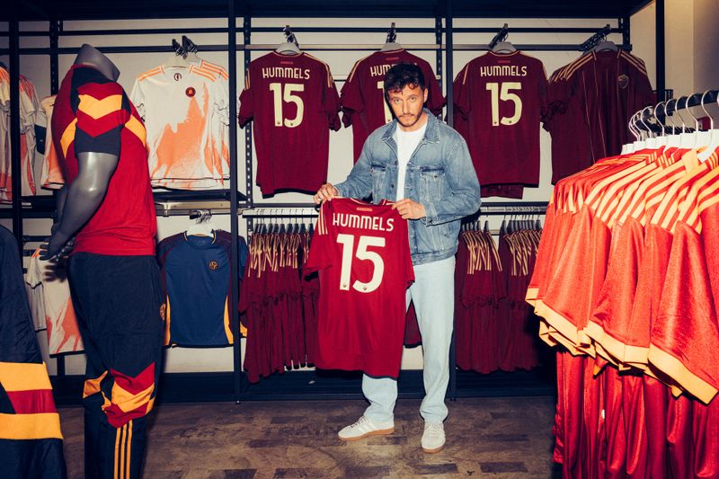 Trikots mit der Aufschrift Hummels dürften im Laufe einer langen Karriere einige über den Ladentisch gegangen sein. Tommi Schmitt hält ehrfürchtig ein Mats Hummels-Trikot in die Kamera.