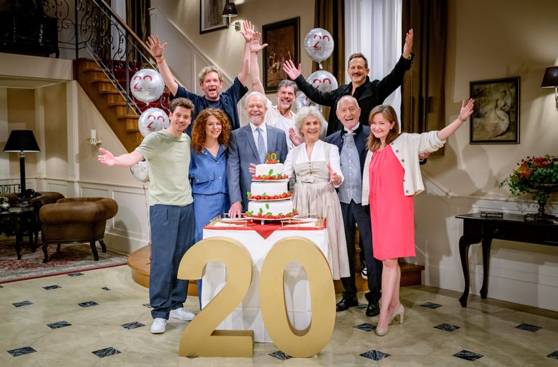 Seit zwei Jahrzehnten begeistert die ARD-Telenovela "Sturm der Liebe" ihr Publikum. Anlässlich des Jubiläums wurde am Set gefeiert. Unter den Gästen befanden sich Produzent Peter Proske-Clayton (hinten links), Gregory B. Waldis sowie Marcus Ammon (hinten rechts), Geschäftsführer Content bei Bavaria Fiction. In der ersten Reihe freuten sich, von links: Anthony Paul, Johanna Graen, Dirk Galuba, Antje Hagen, Sepp Schauer und Lara Okamoto (Redakteurin BR) gemeinsam über dasJubiläum.