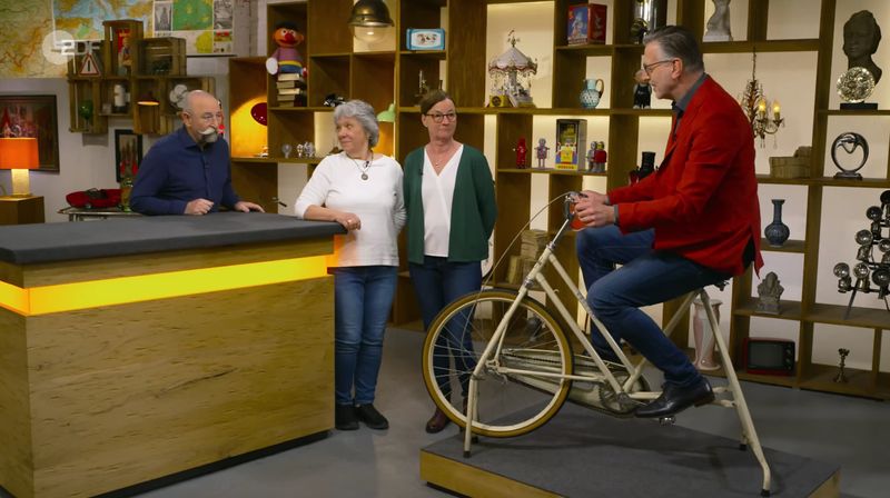 "Detlev, das steht dir", rief Lichter, als er Detlev Kümmel (rechts) auf dem Fitnessrad sah. Der Experte nickte lächelnd und fügte scherzend hinzu: "Ja, ist ja auch ein stehendes Fahrrad." Das Gerät zählte zu den ganz frühen Heimtrainern. Damals erinnerten diese noch an normale Fahrräder, erklärte der Experte. 