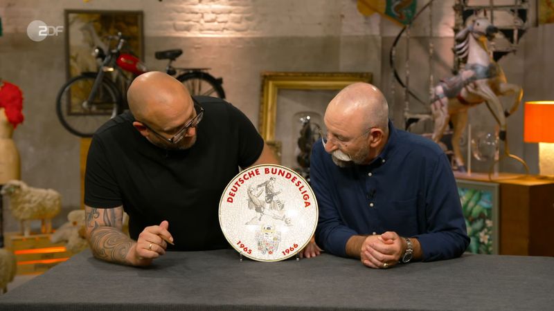 "Da werden einige Herrschaften ziemlich begeistert sein", war Horst Lichter (rechts) sicher. Auf dem Teller las er "1965 bis 1966". Der Moderator fand: "Das ist alt." Er erkundigte sich neugierig bei Sven Deutschmanek, seit wann es die Bundesliga überhaupt gibt.
