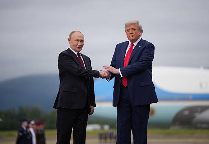 Donald Trump (rechts), Präsident der Vereinigten Staaten, begrüßt seinen russischen Amtskollegen Wladimir Putin am 15. August 2025 bei ihrem Treffen auf dem Flughafen der "Joint Base" Elmendorf-Richardson in Alaska zu Friedensgesprächen. Inzwischen hängt das Bild im Weißen Haus.