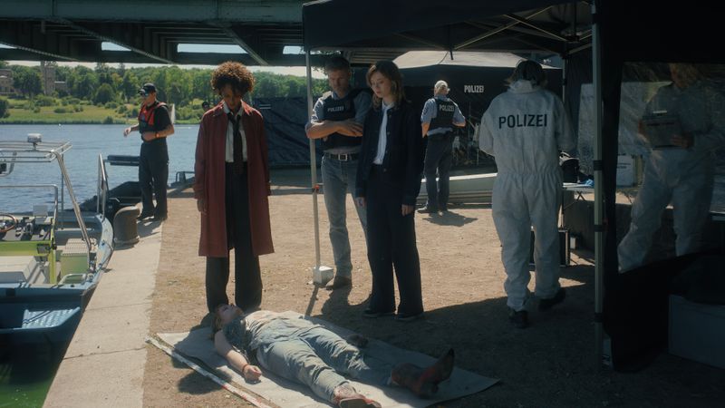 Die Leiche der Studentin Yvonne (Merle Finck-Stoltenberg, liegend) wurde unter der Glienicker Brücke aus dem Wasser der Havel gezogen. Ermittler Max Zeller (Jens Atzorn, dritter von links), Staatsanwältin Dena Paulos (Dennenesch Zoudé, zweite von links) und ihre Referendarin Jasna Nowak (Linda Belinda Podszus) verschaffen sich einen ersten Eindruck.